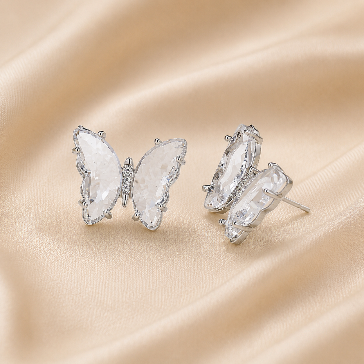 Elegant butterfly zircon earrings displayed on soft fabric background