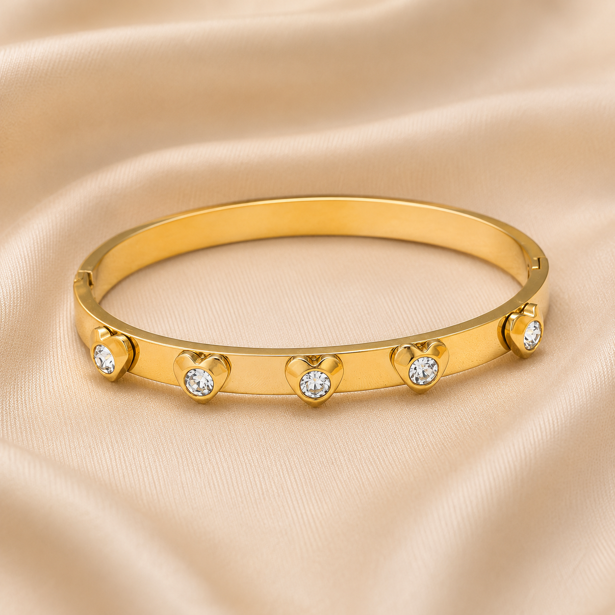 Gold plated zircon heart bangle displayed on luxury fabric background