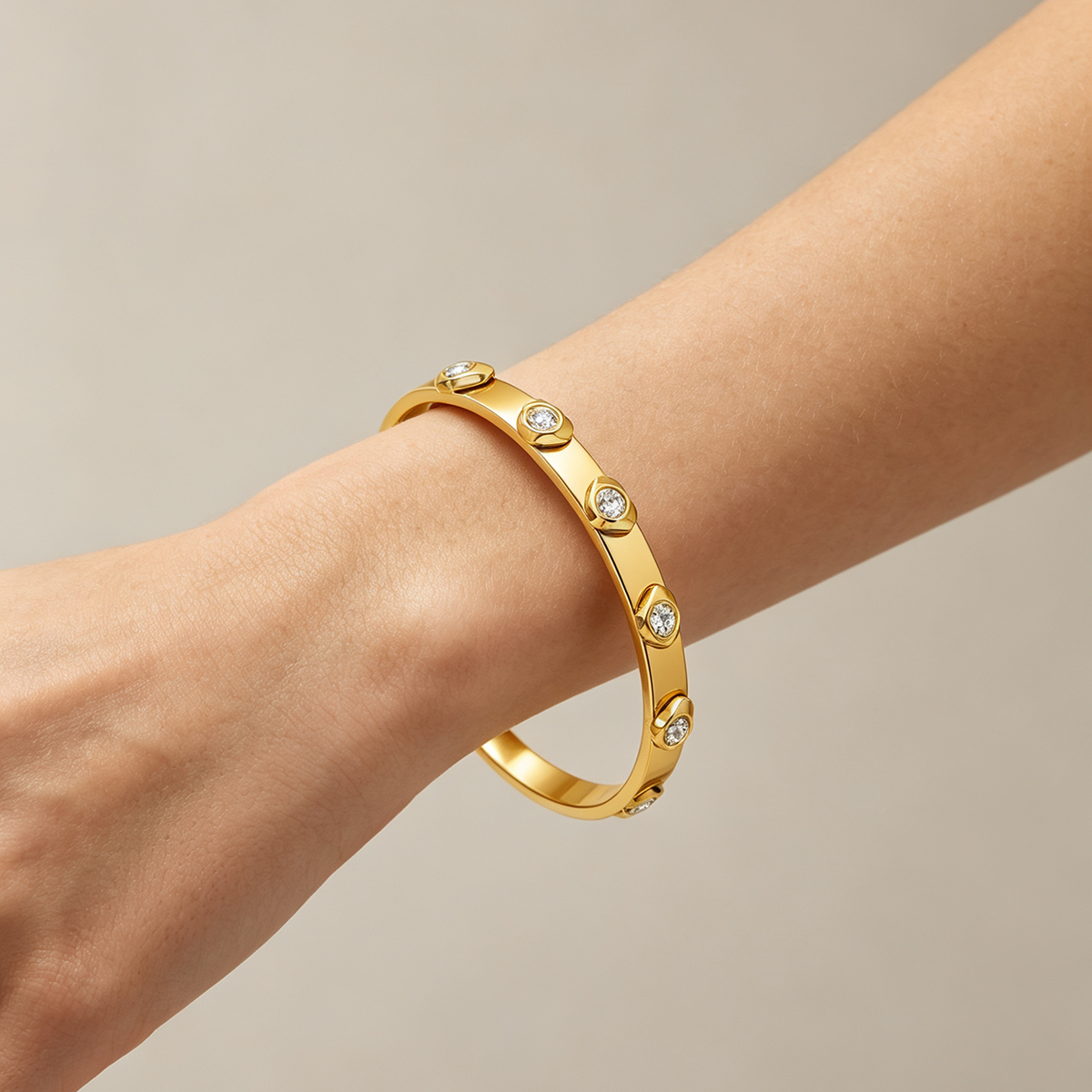 Gold tone zircon heart detail bangle worn on wrist, elegant minimalist bracelet design